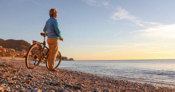 istock Man wearing protective mask watches sunrise at beach 1300689900