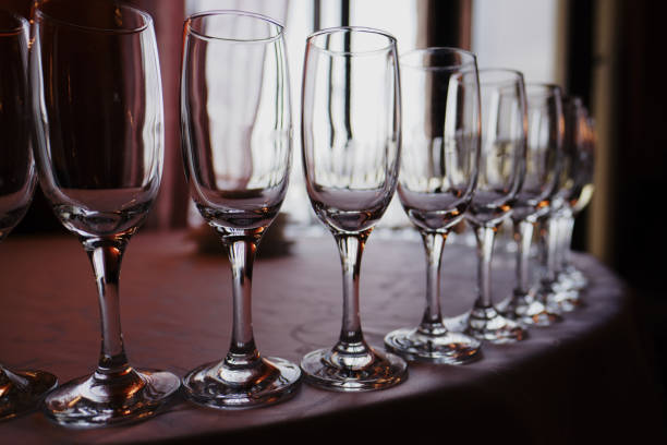 istock Champagne glasses stand in a semicircle in a row on a table covered with a light tablecloth, gloomy lighting, selective sharpness of the image and blurred 1300692245