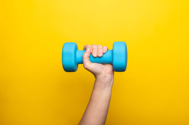 istock Fitness concept with a dumbbell on the yellow backdrop 1300692761