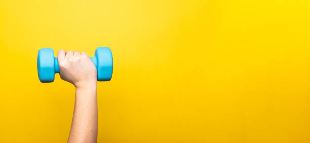 istock Fitness concept with a dumbbell on the yellow backdrop 1300692765