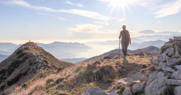 istock Female hiker with walking stick on a sunny mountain top 1300696397
