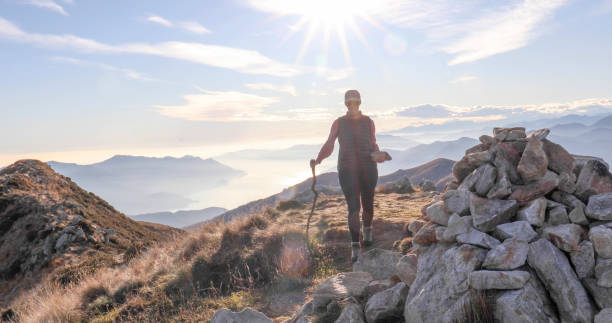 istock Female hiker with walking stick on a sunny mountain top 1300696449