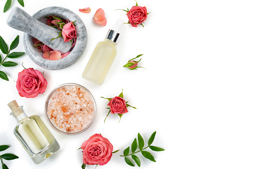 Flat design of rose cosmetics concept of mortar and pestle with rose buds with dropper salt and oil bottle on white background