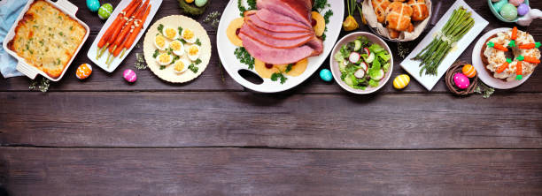 istock Traditional Easter ham dinner. Above view top on a dark wood banner background with copy space. 1300697810