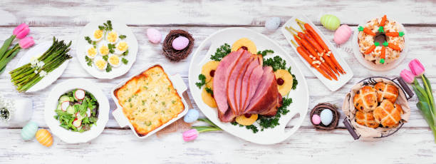 istock Classic Easter ham dinner. Top down view table scene on a white wood banner background. 1300698385