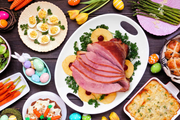istock Traditional Easter ham dinner. Above view table scene on a dark wood background. 1300698584