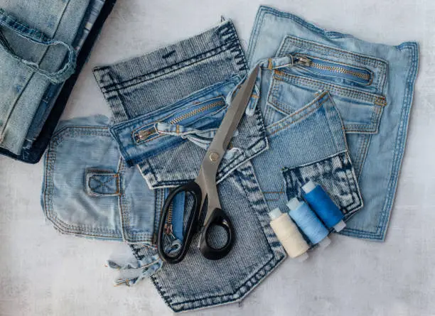 Different jeans pockets, scissors and threads ready to recycle. Concept of things reuse and natural resources preserving.