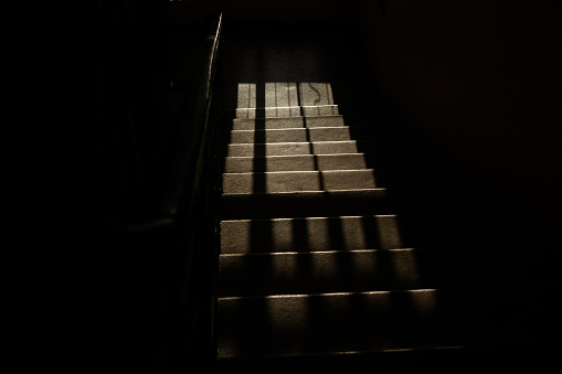 Dark corridor of a building with the stairs receiving the morning light. Silence and loneliness.