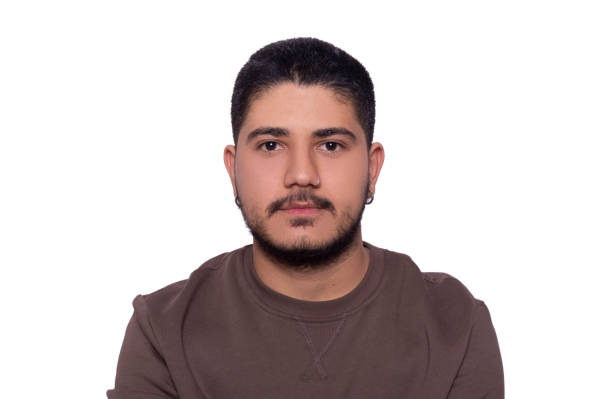 istock Handsome man with short hair standing in front of white background looking towards camera with blank expression. 1300701099