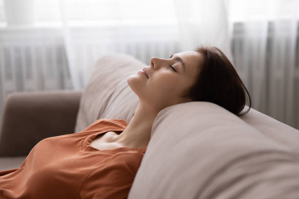istock Serene woman leaning back on couch dreaming with closed eyes 1300701436