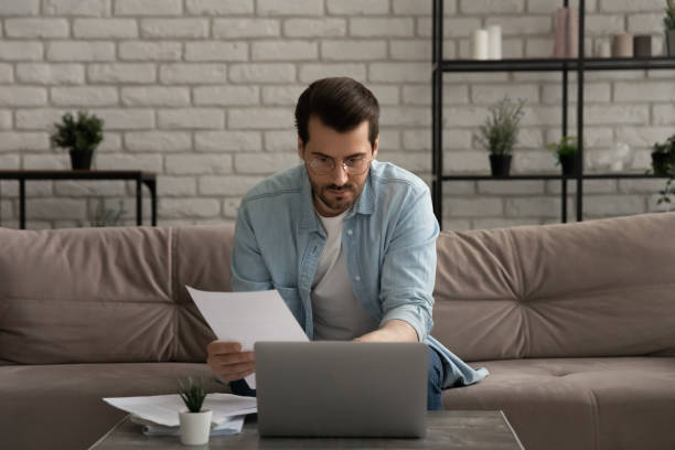 istock Serious thoughtful young man working with documents at home office 1300701486