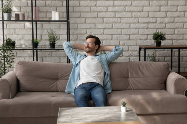 istock Calm millennial man relaxing on comfy sofa after finishing work 1300701520
