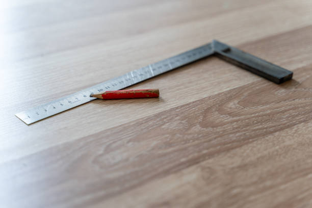 istock Red Carpenter's Pencil and Right Angle's Tool on Laminate Floor after Renovation or Reconstruction Work. DIY Project 1300703504