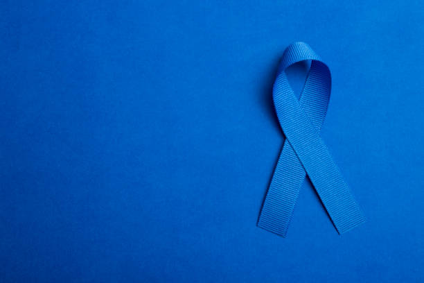 Blue colored ribbon isolated on blue background. Symbol of colon cancer awareness. healthcare and medicine concept. Preventive measures for health Colorectal Cancer Awareness Blue Ribbon for health awarness colorectal cancer photos stock pictures, royalty-free photos & images