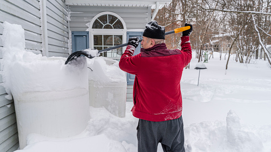Senior retired Caucasian White man cleaning the snow around his home after the winter snowstorm.