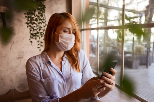 istock Woman in protective mask working online on her mobile phone 1300710315