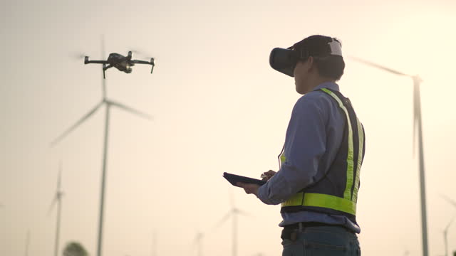 Young Male engineer controlling flying by VR glasses drone working at wind power station at Subset