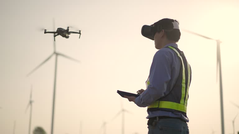 Engineer,Drone,Flying,Construction Industry,Construction Site,Surveyor,Technology, Young Male engineer controlling flying by VR glasses drone working at wind power station at Subset