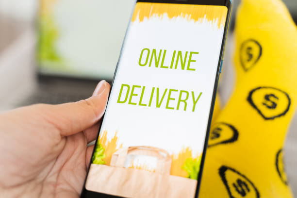 istock Hand with mobile phone. Online internet shopping, order through mobile application. Laptop. Home delivery of food, groceries from grocery store. Paper bag with pasta on screen. Payment by credit card 1300714741