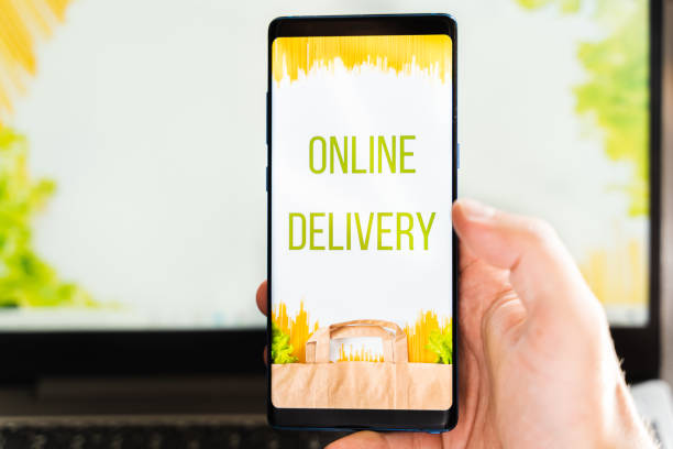 istock Hand with mobile phone. Online internet shopping, order through mobile application. Laptop. Home delivery of food, groceries from grocery store. Paper bag with pasta on screen. Payment by credit card 1300714745