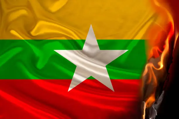 fire burns on the national flag of the state of Myanmar on silk, the concept of tourism, politics, military coup, revolution, civil rights and freedoms