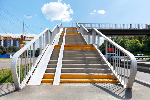High-rise staircase, transition to the other side of the highway. A staircase going up to a pedestrian bridge, an overpass and a crossing over a high-speed highway on a bright sunny day against the backdrop of a blue sky with a cloud. Copy space. footbridge photos stock pictures, royalty-free photos & images