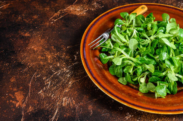istock Fresh green corn salad leaves on a rustic plate. Dark background. Top view. Copy space 1300718177