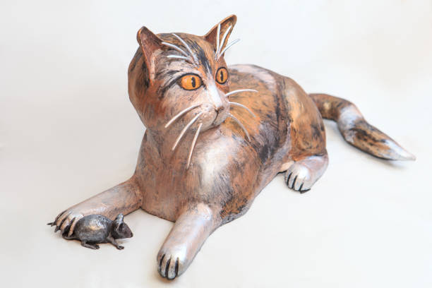 istock Statue of a metal cat holding a mouse on a white background 1300719519