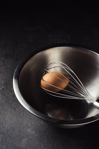 Brown egg with a whisk in metal bowl