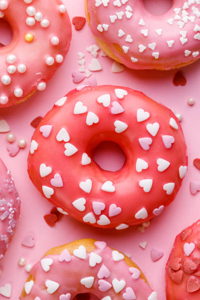 istock Valentine's donuts with icing and sugar sprinkles on a pink background 1300721442