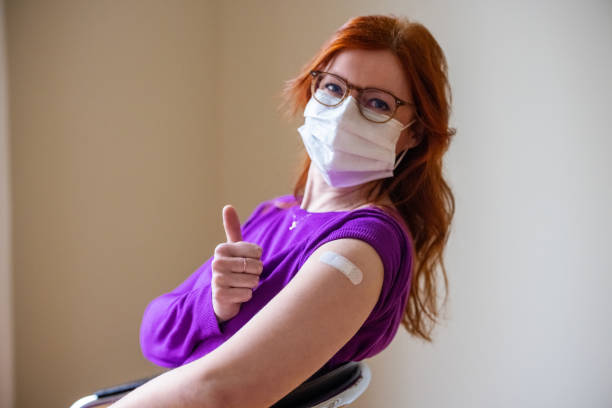 femme affichant des pouces vers le haut après avoir obtenant le vaccin covid-19 - injecting flu virus cold and flu doctors office photos et images de collection