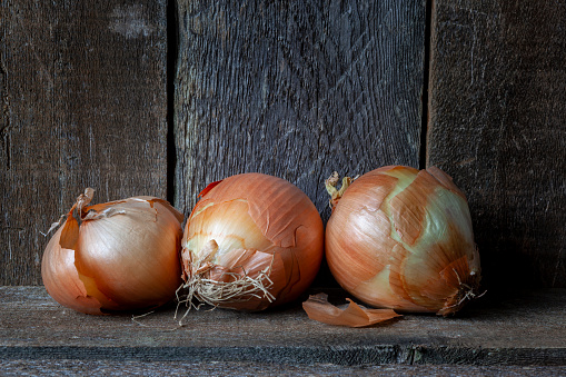 Three fresh onions with a rustic wood background.