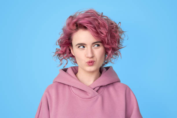 Young woman with pink hair making thoughtful face