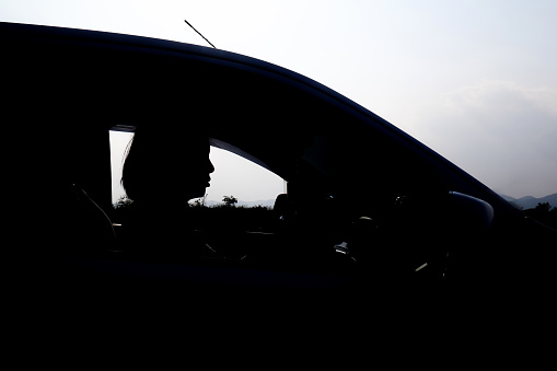 Silhouettes of woman driving a car in sunset