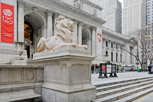 New York, USA - February 1, 2020: Day time view of the New York Public Library building. Opened in 1911, it is a historic landmark in Manhattan. It is located at the intersection of Fifth Avenue and 42nd Street. Its entrance is flanked by a pair of iconic stone lion statues.