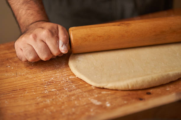 istock hands of a cook on his rolling pin stretching a dough 1300756215