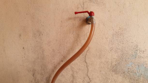 istock Metal faucet red handle with hose isolated on yellow concrete wall. 1300763205