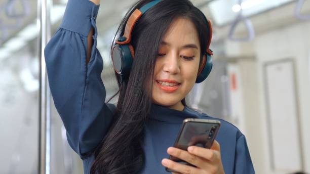 istock Young woman using mobile phone on public train 1300765058