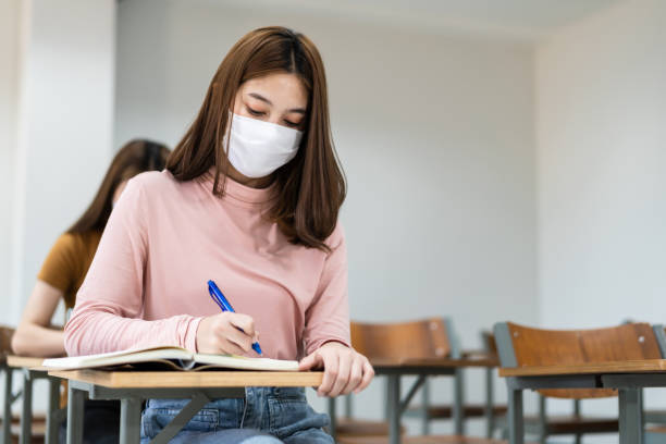 istock Group of college students wearing a face mask and keep distance while studying in the classroom and college or university campus to prevent COVID-19 pandemic. The new college or university campus life 1300765665