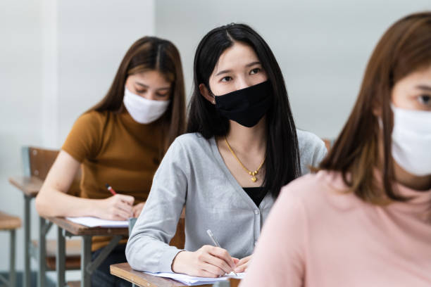 istock Group of college students wearing a face mask and keep distance while studying in the classroom and college or university campus to prevent COVID-19 pandemic. The new college or university campus life 1300765679