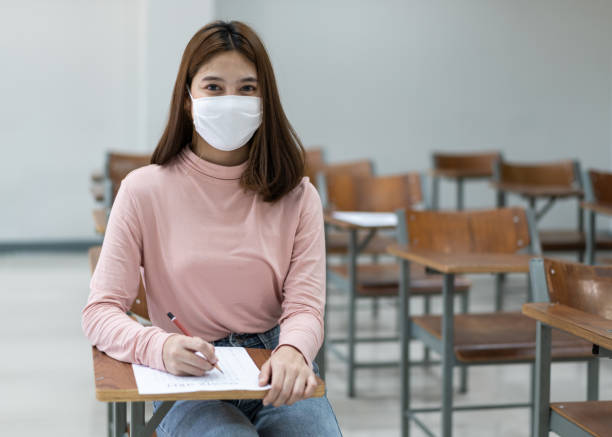 istock Group of college students wearing a face mask and keep distance while studying in the classroom and college or university campus to prevent COVID-19 pandemic. The new college or university campus life 1300765704