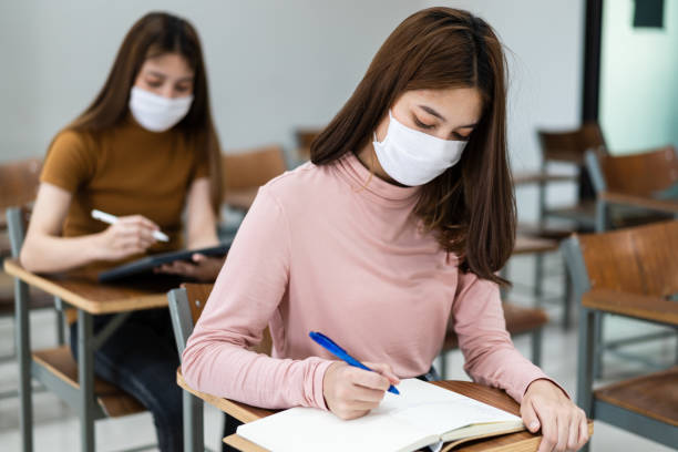 istock Group of college students wearing a face mask and keep distance while studying in the classroom and college or university campus to prevent COVID-19 pandemic. The new college or university campus life 1300765712
