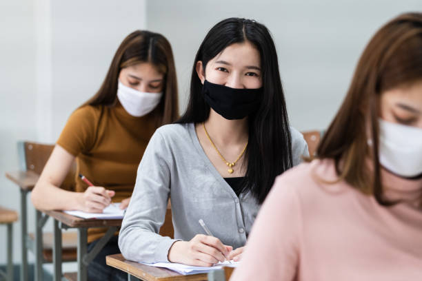 istock Group of college students wearing a face mask and keep distance while studying in the classroom and college or university campus to prevent COVID-19 pandemic. The new college or university campus life 1300766301
