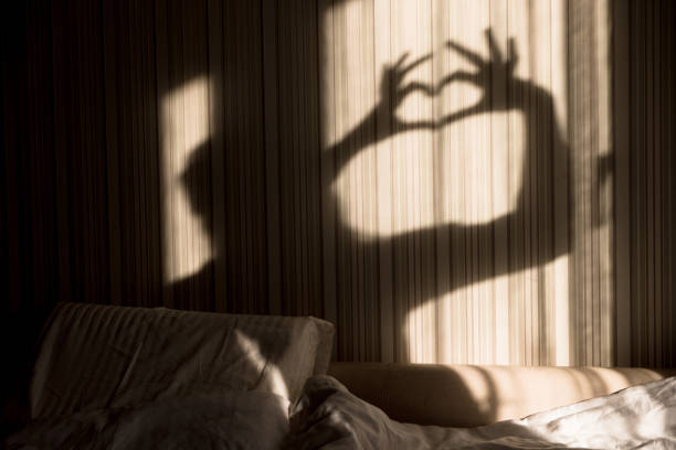 Woman making heart shadow with her hands on the wall. World mental health day, hope and love. Valentines 14 February stock photo