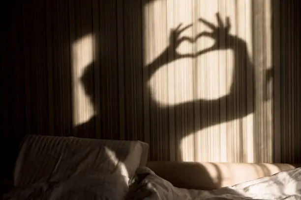 Woman making heart shadow with her hands on the wall. World mental health day, hope and love. Valentines 14 February.