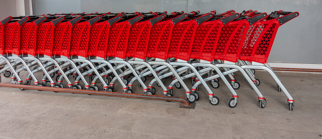Row of chrome and red plastic shopping carts at supermarket