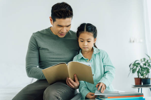istock Asian father and mother reading book with daughter 1300769087