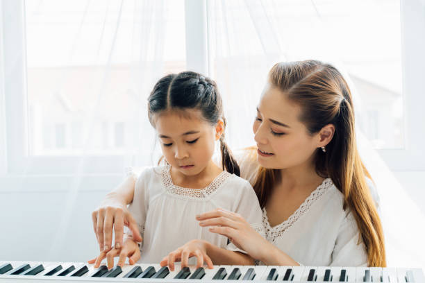 istock Asian mother watching young daughter play keyboard 1300769088