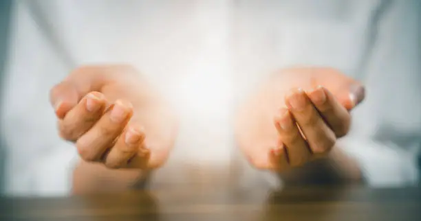 Woman hands praying (makes a dua) and light on palm.