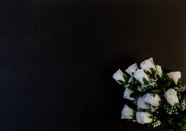 istock Flat Lay, postcard for death, funeral. White roses on a black background 1300769736